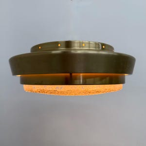 May include: A circular flush mount ceiling light fixture featuring a tiered brass metal frame with a series of small circular perforations along the top edge and a textured, translucent glass diffuser at the base that emits a warm glow.