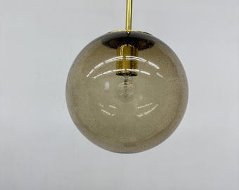 May include: A contemporary pendant light featuring a spherical, speckled, amber glass shade. The light fitting has a gold-coloured metal stem and a black cord. The bulb is visible within the glass sphere.