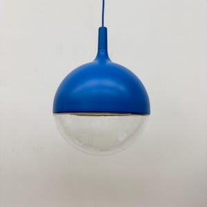 Op de afbeelding: Een moderne hanglamp met een bolvormig ontwerp. De bovenste helft is helderblauw, terwijl de onderste helft van helder glas is. Een blauw snoer en steel lopen vanaf de bovenkant, waardoor een strakke, eigentijdse uitstraling ontstaat. Ideaal voor modern interieur.
