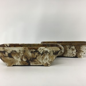 Op de afbeelding: Twee rechthoekige keramische potten met een bruin en wit gemarmerd glazuur. De potten hebben een rechthoekige vorm met licht uitlopende zijden en een platte bodem.