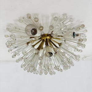Peut inclure: Un lustre en laiton et en cristal avec un design en étoile. Le lustre a de nombreux bras en cristal transparent avec de petites ampoules à l'extrémité de chaque bras.