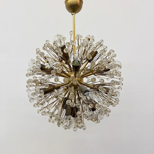 Op de afbeelding: Een ronde, gouden kroonluchter met meerdere kristal-achtige accenten en heldere gloeilampen. De kroonluchter heeft een modern ontwerp en is perfect voor een modern huis.