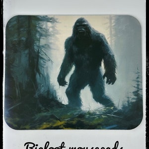 Pode incluir: Um mousepad preto e branco com uma ilustração de Bigfoot em um cenário de floresta nebulosa. O texto "Bigfoot mousepads" é impresso abaixo da imagem.