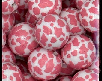 May include: A close-up of a group of pink and white polka dot beads. The beads are arranged in a random pattern and are all the same size. The beads are glossy and have a smooth surface.