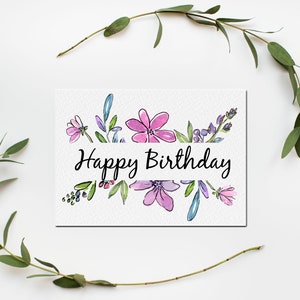 Może przedstawiać: Biała kartka z akwarelowym obramowaniem kwiatowym i tekstem "Happy Birthday" czarnym pismem.