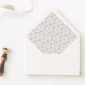 May include: A white envelope with a flap. The inside of the flap is lined with a pattern of small, light brown and pink floral sprigs on a white background. A gold and brown wax seal is next to the envelope.