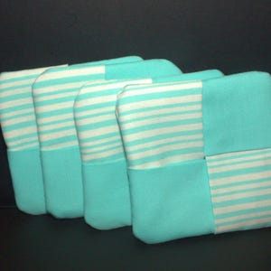 May include: Five turquoise blue fabric pouches with white stripes. The pouches are lined up in a row, with the stripes running horizontally.