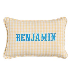 May include: A rectangular pillow with a yellow and white gingham pattern. The word "BENJAMIN" is embroidered in blue across the center. The pillow has a soft, rounded shape and a white border.