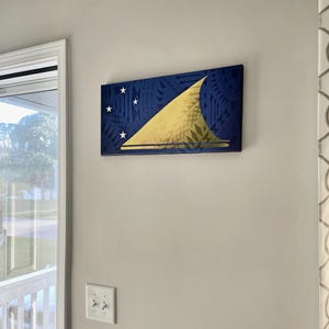 May include: A blue and gold canvas print of the flag of the Independent State of Samoa. The flag features a white triangle with five white stars and a gold sail on a blue background.