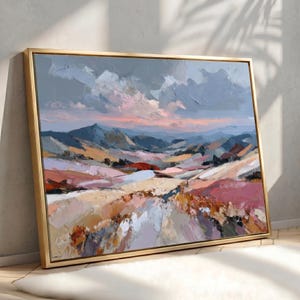 May include: A landscape painting in a gold frame featuring thick, textured brushstrokes of a mountain range under a cloudy sky. The color palette includes shades of dusty pink, soft orange, muted blue, grey, and cream, depicting rolling hills.