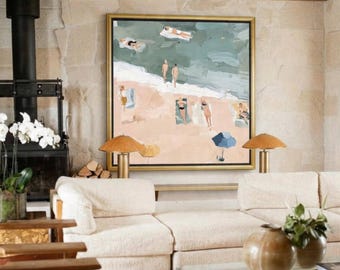 Op de afbeelding: Een groot vierkant ingelijst schilderij met een strandscène waarop mensen op het zand ontspannen en in de oceaan zwemmen. Het kunstwerk heeft een gedempt kleurenpalet van beige, zachtgroen en blauw, met een enkele blauwe parasol op het zand.