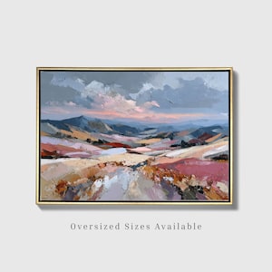 May include: An oil painting in a gold frame depicting a landscape with rolling hills in shades of pink, orange, and blue under a cloudy sky. The textured brushstrokes create a layered effect across the terrain, with the text Oversized Sizes Available.