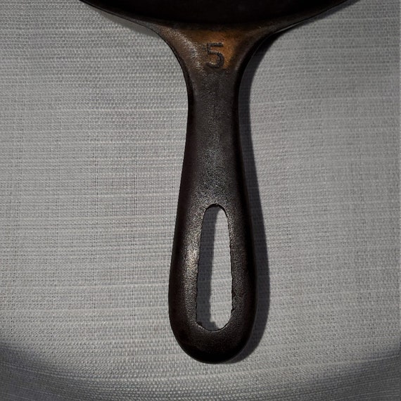 Old cast iron frying pan hanging from hook and rod Stock Photo by  ©CookiesForDevo 93661796