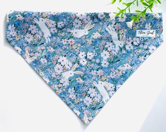 May include: A blue bandana with a white floral pattern and white bunnies. The bandana has the text "Flora Soul Design" printed on it.