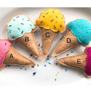Puede incluir: Cinco conos de helado de fieltro en diferentes colores y sabores. Los conos est&aacute;n etiquetados de la A a la E. Los sabores de helado son rosa, azul claro, amarillo, azul y morado.