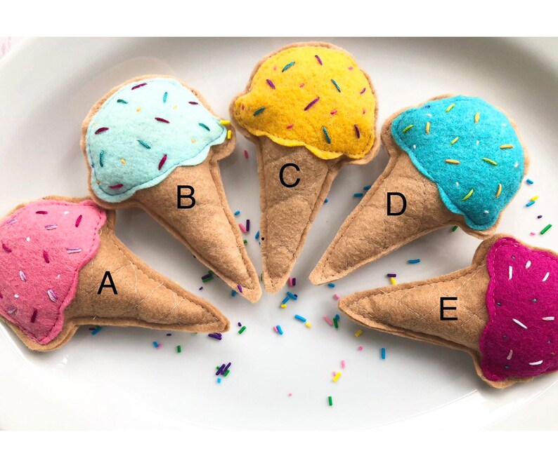 Puede incluir: Cinco conos de helado de fieltro en diferentes colores y sabores. Los conos est&aacute;n etiquetados de la A a la E. Los sabores de helado son rosa, azul claro, amarillo, azul y morado.