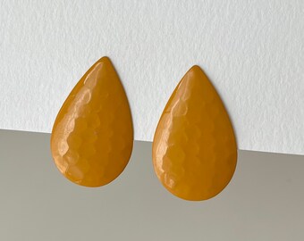 May include: A pair of teardrop-shaped earrings in a warm yellow color. The earrings have a hammered texture, giving them a unique and textured look.