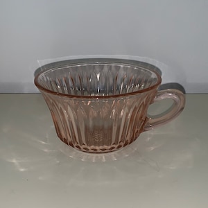 May include: A pink glass teacup with a fluted design.