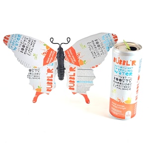 May include: A silver can of Bubbl'r Antioxidant Sparkling Water with a blood orange and mango flavor. The can has a butterfly design on it with the text "That Boosts Energizes Restores Balance".
