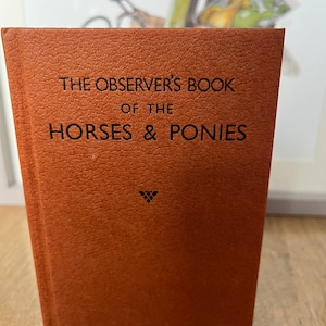Puede incluir: Un libro encuadernado en cuero marrón titulado "The Observer's Book of the Horses & Ponies" con un pequeño símbolo de triángulo negro en la portada.