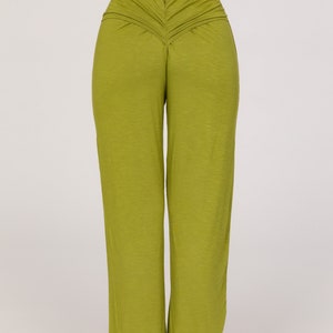 May include: Olive green wide-leg trousers with a ruched back waist detail. The model is wearing a white top. The trousers are made from a soft, flowing fabric. The trousers are a vibrant shade of green.