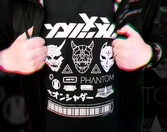 May include: Black t-shirt with a white graphic design featuring the text "PHANTOM" and three stylized masks. The masks are a demon, a geometric design, and a fox mask. The text "MANJIYASAR" is also included in the design.