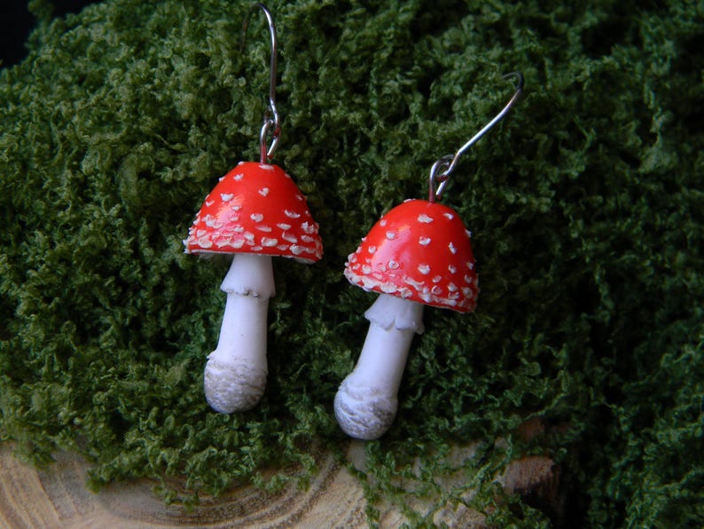 Op de afbeelding: Een paar rode en witte paddenstoel oorbellen met zilveren haakjes. De paddenstoelen hebben witte stippen en een witte steel.