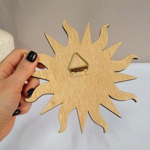 May include: Wooden sun wall decor with a gold-colored hanging hook on the back.