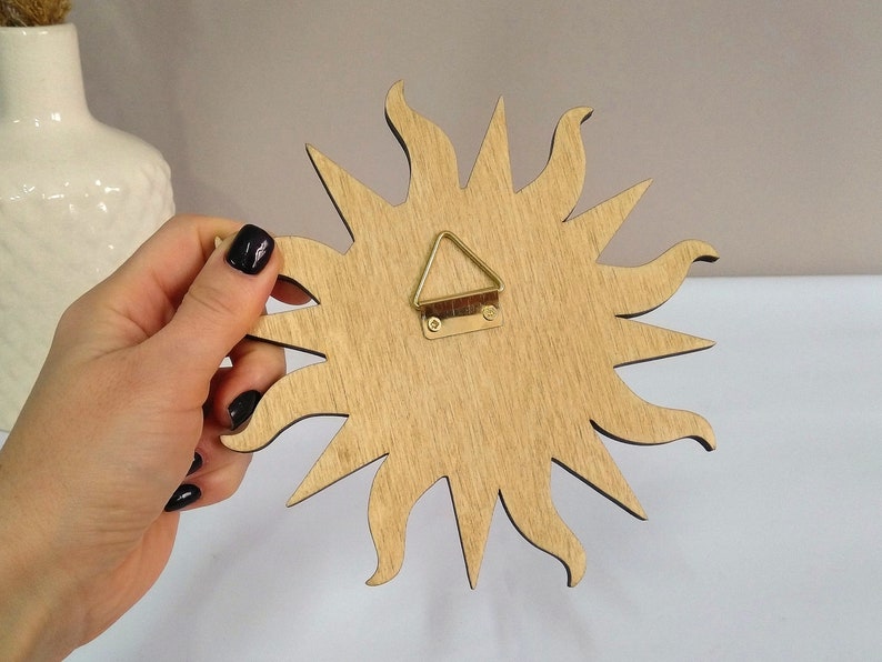 May include: Wooden sun wall decor with a gold-colored hanging hook on the back.