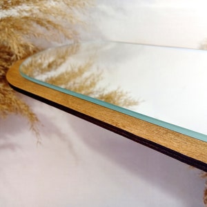 May include: A wooden framed oval mirror with a light wood frame and a clear glass surface.
