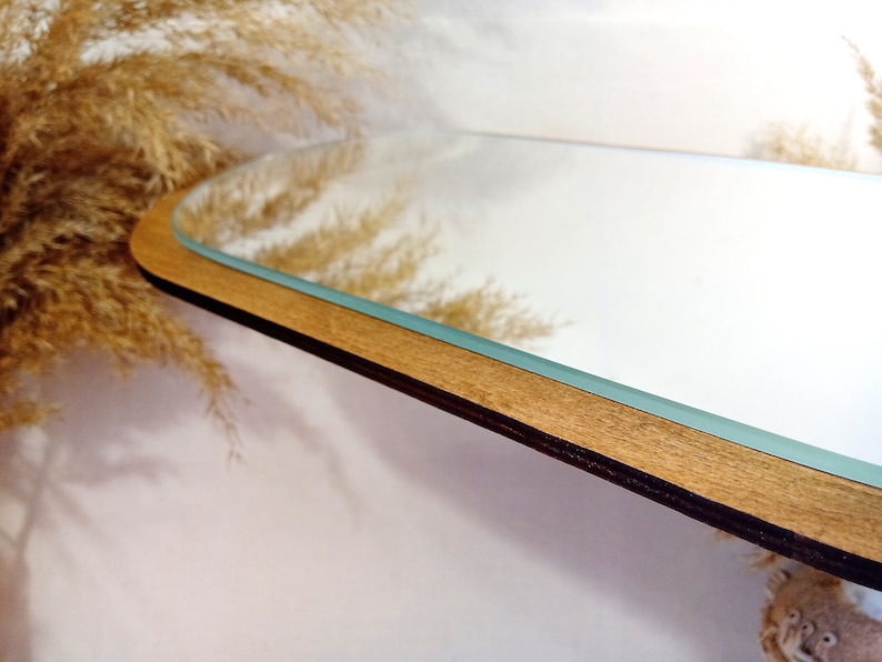 May include: A wooden framed oval mirror with a light wood frame and a clear glass surface.