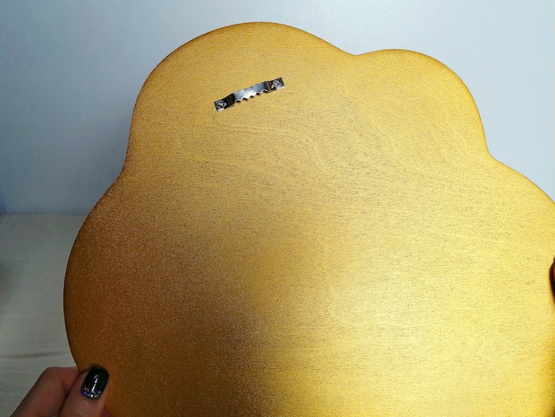 Pu&ograve; includere: Una targa in legno a forma di nuvola di colore dorato con un gancio di metallo per appendere sul retro.