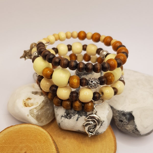 Bracelet de perles en bois marron. Grosses perles en bois naturel blanches et brunes. Bracelet fait main à mémoire de forme avec breloques tortue et dauphin.