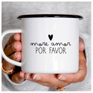 Könnte beinhalten: Weiße Email Tasse mit schwarzem Rand und Henkel. Die Tasse hat ein schwarzes Herz und den Text "more amor POR FAVOR" in Schwarz.