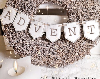 May include: A white felt banner with the word "ADVENT" embroidered in brown thread hangs on a brown twig wreath. The wreath is decorated with small, sparkly stars and moons. A white candle sits in front of the wreath.