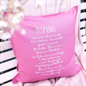 Peut inclure: Un coussin rose avec du texte blanc qui dit "FR&Uuml;HLING" et une liste de mots d&eacute;crivant le printemps en allemand. Les mots sont "blauer Himmel", "die Natur erwacht", "gute Laune", "frische Blumen", "gr&uuml;ne Bl&auml;tter", "k&uuml;hle Sonnentage", "Tatendrang", "und ergil", "Vogelgezwitscher", "Blumen und", "Gem&uuml;sepflanzen", "Neuanfang".