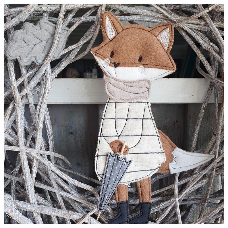 Peut inclure: Un renard en feutre marron portant une robe &agrave; rayures blanches et noires et une &eacute;charpe grise, tenant un parapluie gris et blanc &agrave; pois.