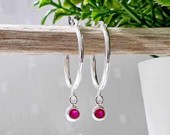 Pode incluir: Brincos de argola de prata com um charme de pedra preciosa rosa pendurado.