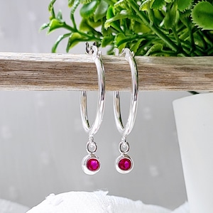 Op de afbeelding: Zilveren creolen met een hangende roze edelsteenbedel.