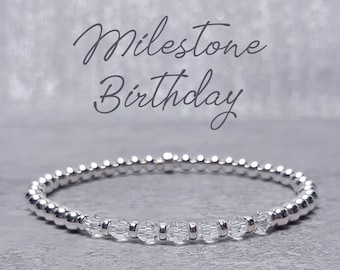 Könnte beinhalten: Ein silbernes Armband mit klaren Kristallperlen. Das Armband liegt auf einem grauen Hintergrund mit dem Text "Milestone Birthday" und "April Birthstone Crystal".