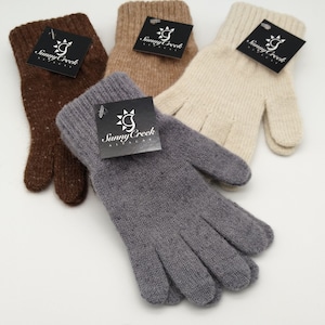 May include: Three pairs of alpaca gloves in brown, beige, and gray. Each pair has a black tag with the words "Sunny Creek Alpaca" and a sun graphic.