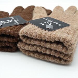 May include: Two pairs of fingerless gloves, one brown and one beige, folded and stacked. Both pairs have a black tag with the text "Sunny Knitting" and a sun graphic.