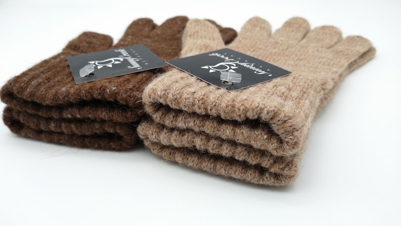 May include: Two pairs of fingerless gloves, one brown and one beige, folded and stacked. Both pairs have a black tag with the text "Sunny Knitting" and a sun graphic.