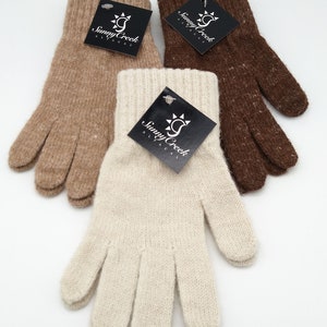 May include: Three pairs of alpaca gloves in brown, beige, and white. Each pair has a black tag with the words "Sunny Creek Alpacas" and a sun graphic.