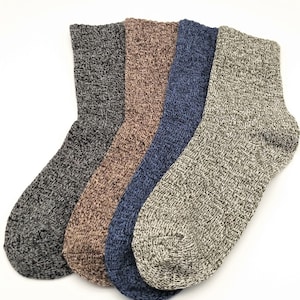 Puede incluir: Cuatro pares de calcetines de diferentes colores: gris, marrón, azul y beige. Los calcetines están hechos de una tela texturizada y tienen un patrón de canalé.