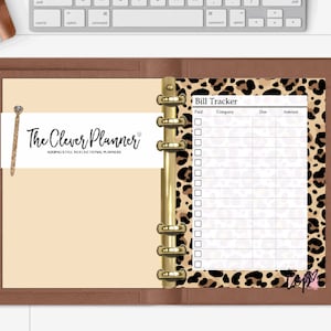 May include: A brown leather bound planner with a leopard print page insert. The page insert has a bill tracker with columns for paid, company, due, and amount. The planner has gold rings and a gold bookmark.