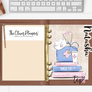 May include: A brown leather planner with a gold ring binder. The left page has a beige background with the text "The Clever Planner" and a brown tassel. The right page has a sticker with a nurse's hat, stethoscope, first aid kit, coffee cup, and books with the text "Physiology", "Nurse Life", and "Anatomy of a Super Nurse". The sticker also has the name "Natasha" and a pink heart.
