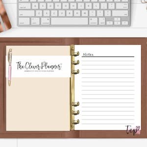 May include: A brown leather bound planner with gold rings. The planner has a white page with lined paper and the text "Notes" at the top. The planner also has a white page with the text "The Clever Planner" and a pen.