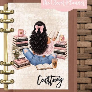 May include: A personal planner with a gold-tone metal ring binding featuring an illustration of a person with long dark hair and a pink bow, sitting among stacks of books, a pink mug, a candle, and a drink, with the name Courtney written below.