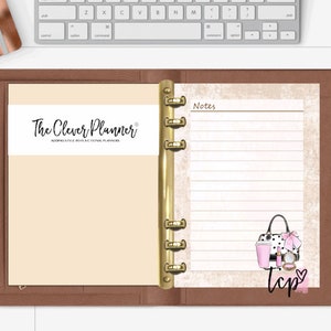 May include: A brown leather bound planner with gold rings. The left page has a white label with the text "The Clever Planner" and the right page has the text "Notes" at the top and a lined section for writing. The right page also has a sticker with a black and white polka dot handbag, a pink coffee cup, a pink lipstick, and a pink heart with the text "tcp" in black.